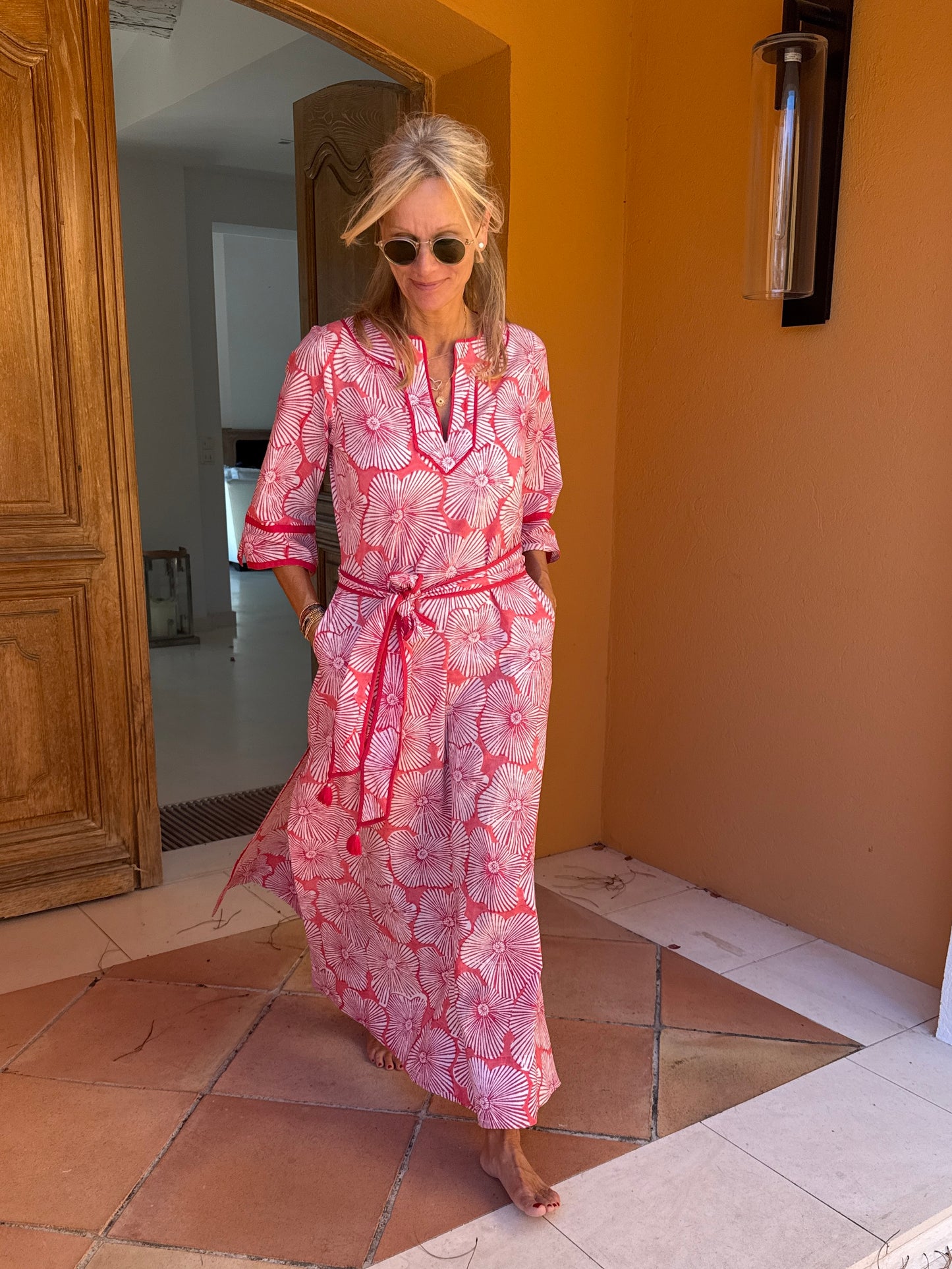 Woman in a pink patterned dress standing in a doorway.