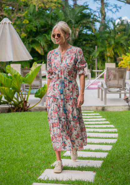 Woman in a floral dress standing on a stone path in a garden