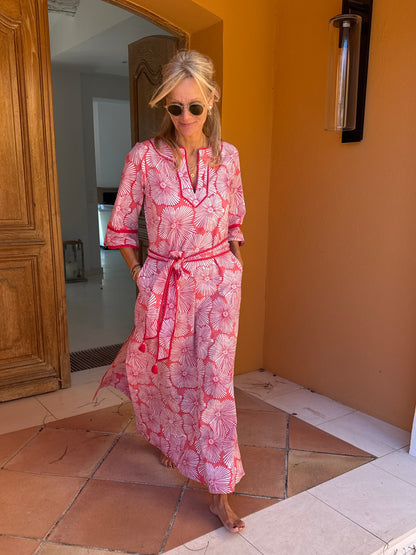 Woman in a pink patterned dress standing in a doorway.